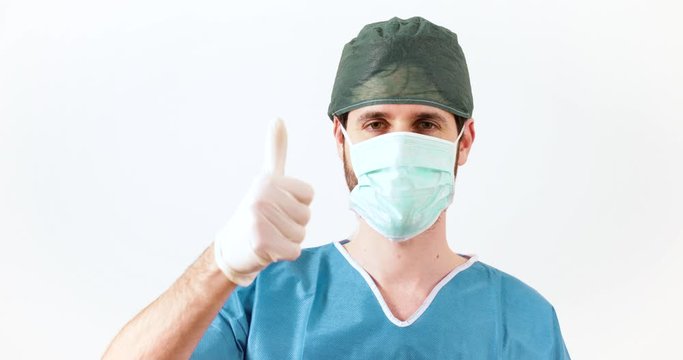 Medico chirurgo fa il pollice in su di fronte uno sfondo bianco.