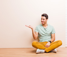 young arabian man feeling happy and smiling casually, looking to an object or concept held on the...