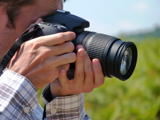 Man taking shots with his new digital photographing camera outdoors in the nature, sunny day