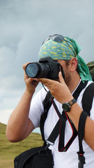 Man taking shots with his new digital photographing camera outdoors in the nature, sunny day