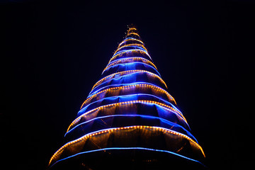 Neon Christmas tree with yellow and blue lights on a black background