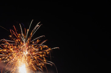 Photo of a single yellow, orange and red firework on a black background
