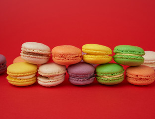 Obraz na płótnie Canvas pile of multi-colored baked macarons almond flour cakes on a red background