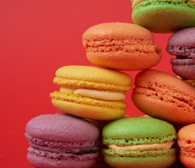 yellow, purple, green round baked macarons cakes on a red background