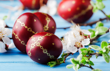 Red Easter eggs. white flowers and willow branches on gentle Easter blue wood background