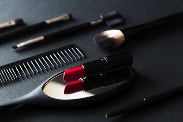 black makeup equipment and tools and red lipstick on black background
