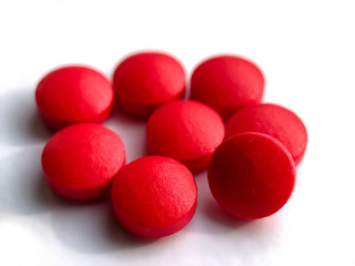 Round pills of red color isolated on white photo.Health concept.
