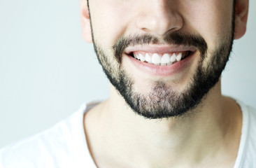 Obraz premium Young man with beautiful smile on grey background. Teeth whitening