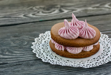 Marshmallows sandwiches made from chocolate dough and blueberry marshmallows. On a lace napkin, on brushed pine boards. Close-up shot.