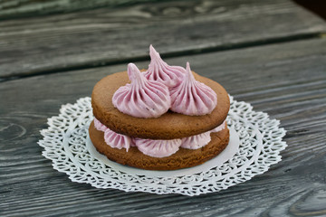 Marshmallows sandwiches made from chocolate dough and blueberry marshmallows. On a lace napkin, on brushed pine boards. Close-up shot.