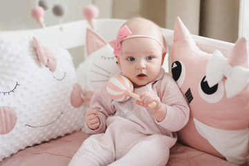 Beautiful baby girl in pink. Cute baby wearing pink body with pink flower headgear. Healthy baby in bed