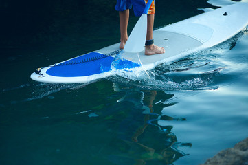 Stand Up Paddling in the sea. SUP. Guy Training in the morning on Paddle Board near the rocks.