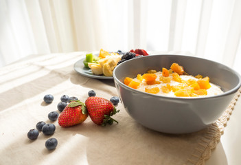 Healthy breakfast with bowl of organic oatmeal porridge and plate of mix fresh fruits with copy space.Healthy lifestyle concept.
