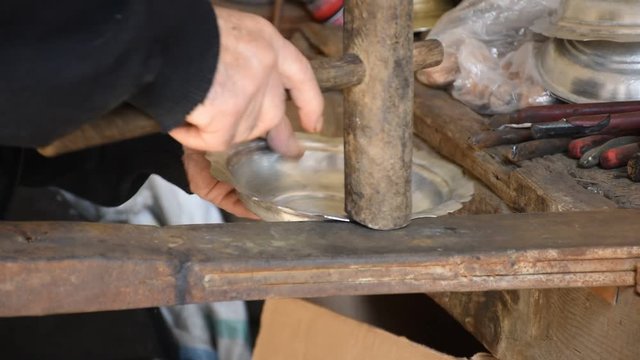 a copper plate corrected by the hands of a copper worker. straightens the plate by hitting the edge with a wooden mallet.