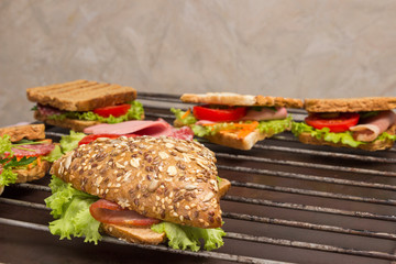 Grilled sandwich with  bacon, salami, cheese and salad on metal grill