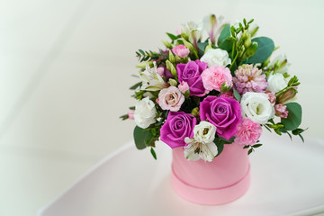 Bouquet of bright fresh flowers in a pink pot on a light gray background