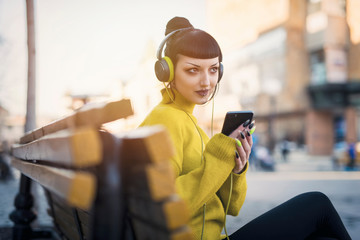 Beautiful gothic girl listening her music by headphones and walk