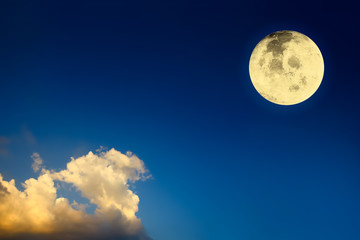 Naklejka na ściany i meble Dramatic atmosphere panorama view of bright and shiny full view of Big Moon on dark blue twilight sky background with golden clouds.Image of moon furnished by NASA.