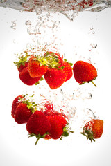 Strawberries falling into water causing bubbles all around it. Healthy food concept