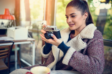 Portrait of beautiful young woman taking photos with vintage camera