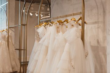 Fototapeta na wymiar a lot of beautiful white wedding dresses on hangers in the store
