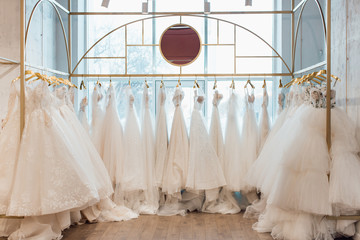 a lot of beautiful white wedding dresses on hangers in the store