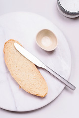 Breakfast setting. Empty marble tray, bowles, knife and piece of bread on grey concrete background. Flatlay.  Selective focus