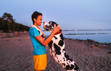 Cheerful male owner hugging with dog on beach