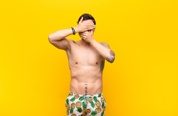 young handsome man covering face with both hands saying no to the camera! refusing pictures or...