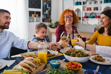 family sits at the dining table and having dinner party at home. making a toast