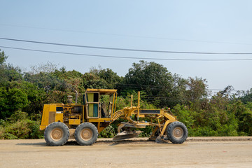 Fototapeta premium The backhoe or grader is working on the highway site with soil and dirt in the sunny day. 