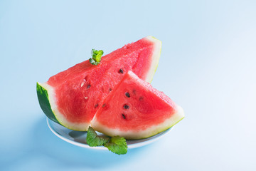 Fresh watermelon on light blue background. Watermelon slices on a plate. Healthy Summer Snack Concept, copy space