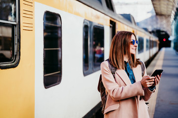 young woman at train station using mobile phone. Travel concept