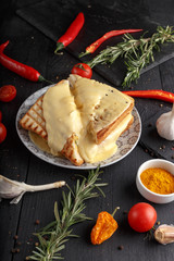 Appetizing sandwiches with tomato cheese and herbs with ingredients on a black wooden table