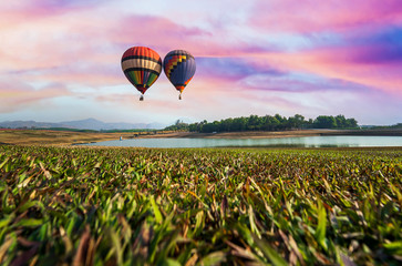 Hot-air balloons flying in colorful sky. Hot air balloons flies in beautiful sky and grass field with wide angle shot. .