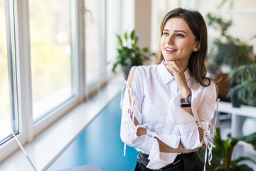 Confident young business woman stands in the office