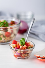 A small bowl of garbanzo bean salad garnished with basil, ready for eating.