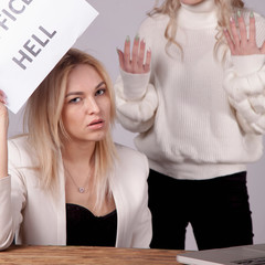 Conflicts of office as risk for business. Female worker holds sign OFFICE HELL.