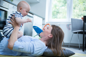 Happy mother playing with her baby at home