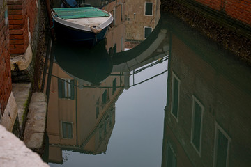 Fototapeta na wymiar Canal poco concurrido en la ciudad de Venecia solitaria. Reflejos en el agua. 