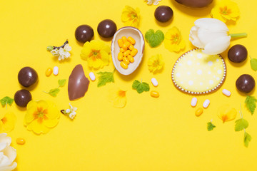Easter yellow background with chocolatte eggs,    candy and spri