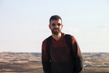 Happy young man with sunglasses in the desert
