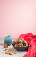 Chocolate caramel ball candies with almonds and a cup of coffee on a gray concrete background and red textile. Side view, copy space, selective focus.
