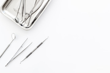 Stomatological tools in tray on dentist's desk on white background top-down frame copy space