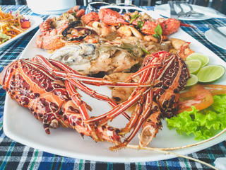 Closeup toned food photo of prawn, langoustines, lobsters and squids on big dish at seafood restaurant
