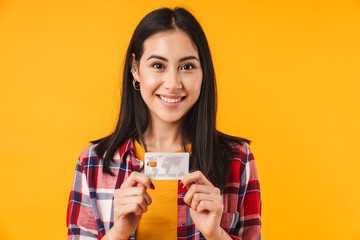 Photo of pleased brunette woman smiling while holding credit card