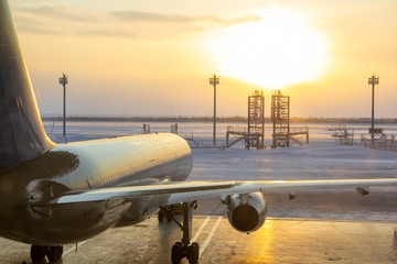 The plane stands in the hangar at sunrise. A frosty day and an airplane, view from the back. Preparing the aircraft for departure. Winter plane ready to fly. Maintenance hangar