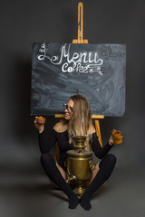 against the background of a chalkboard with a blank for the cafe menu, holding brown clay mugs. In the foreground is a copper samovar