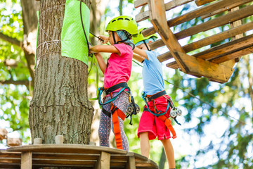 adventure climbing high wire park - children on course rope park in mountain helmet and safety equipment