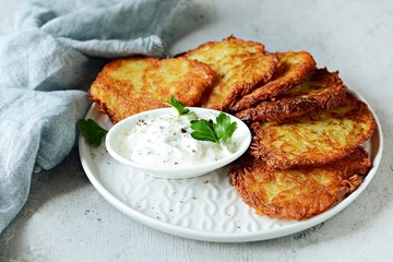 Crispy potato pancakes with green salad and yogurt sauce. Stack of potato fritters